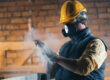 Man dusting hands while wearing respirator
