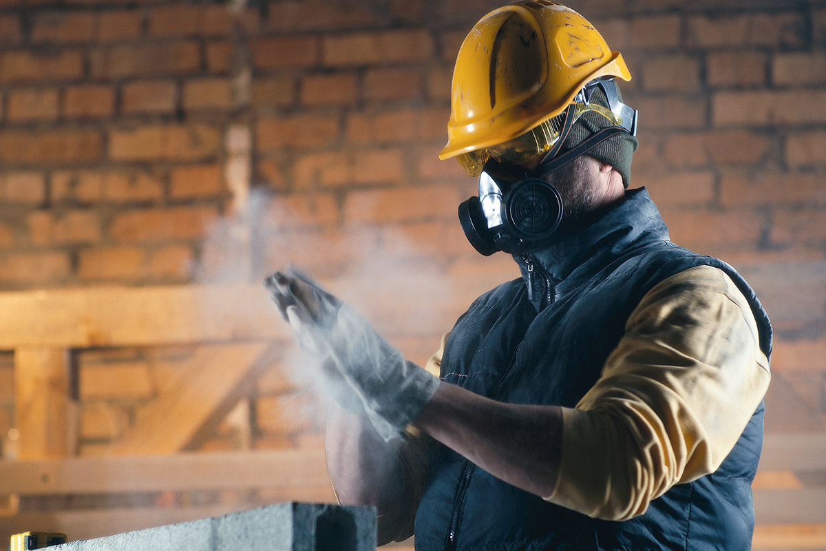 Man dusting hands while wearing respirator